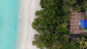 An aerial view of a beach with clear turquoise waters, a sandy shore, and dense green foliage. - ARIA Beach Ukulhas (Ukulhas)
