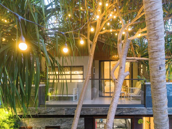 A modern building with a glass facade, outdoor seating area, and string lights. - ARIA Beach Ukulhas (Ukulhas)