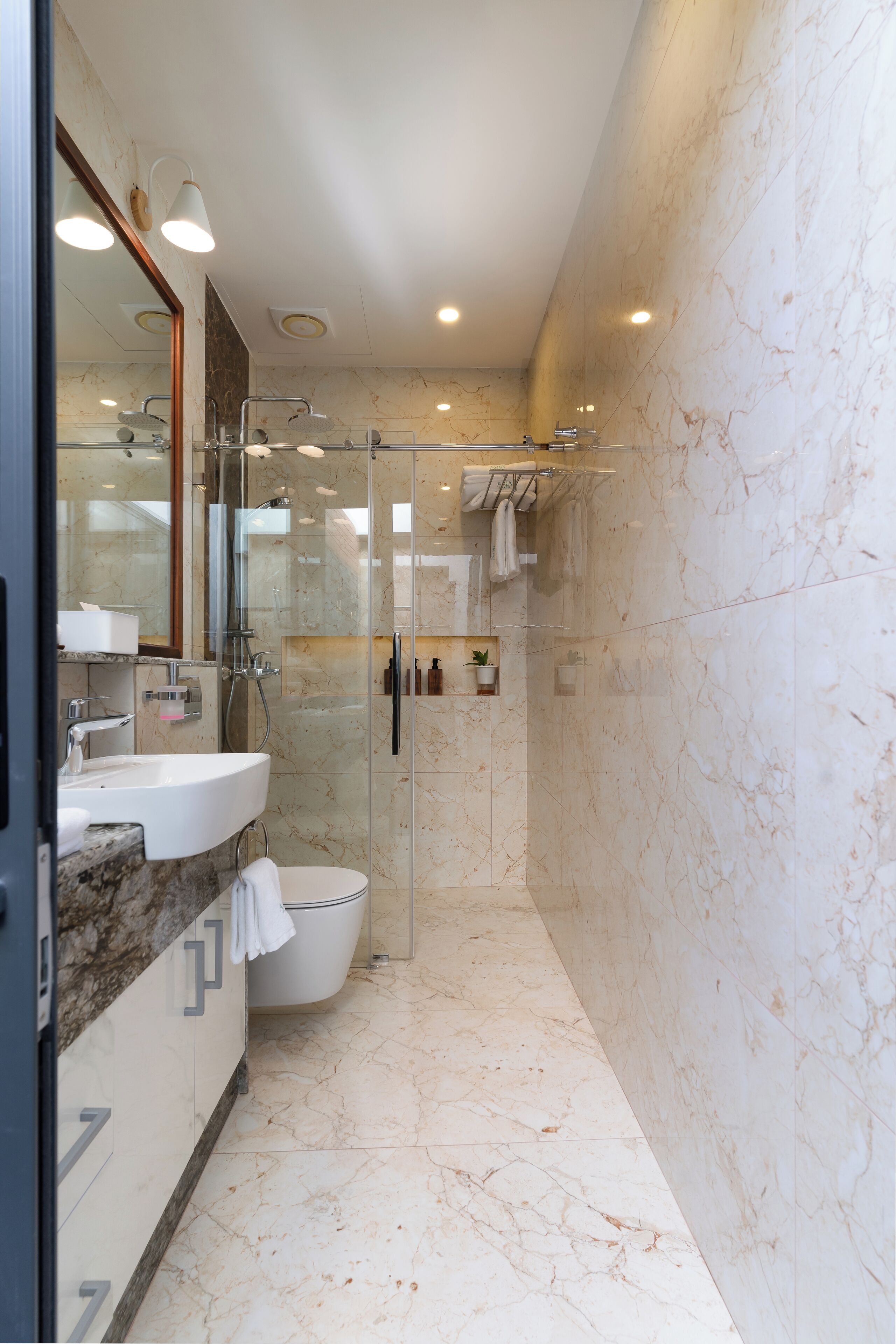Un bany modern amb dutxa de vidre, un lavabo de marbre i un mirall gran.