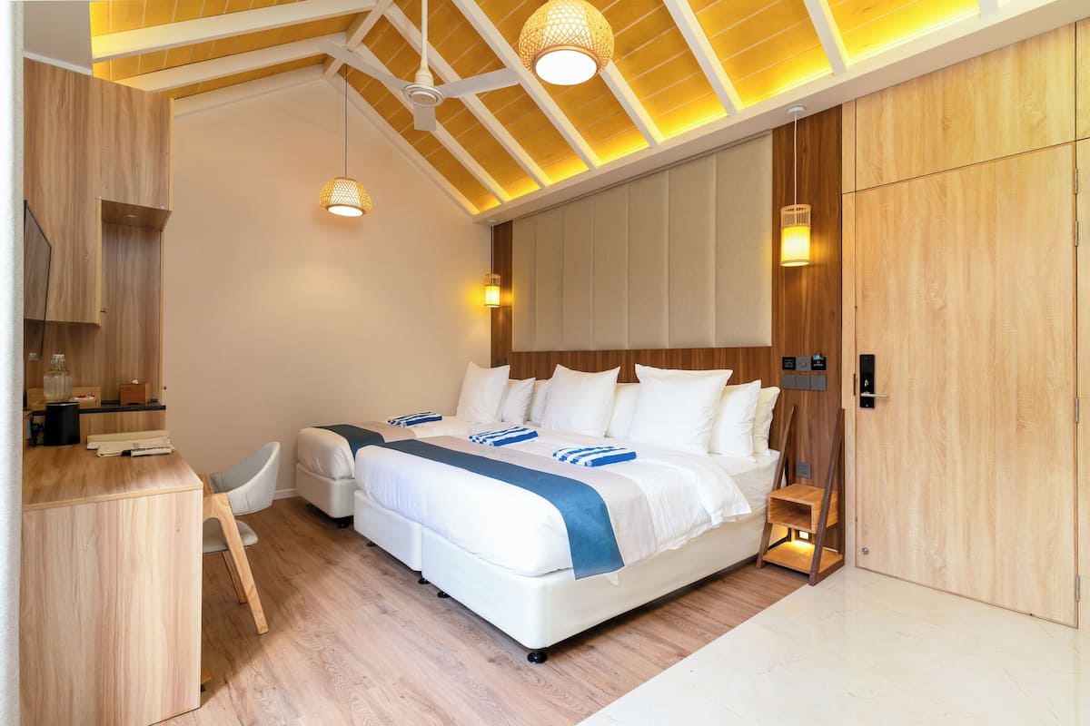 A modern bedroom with a large bed, wooden flooring, and built-in wardrobe.