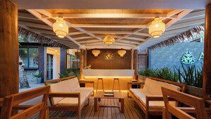 An outdoor seating area with wooden furniture and hanging lights. - ARIA Beach Ukulhas (Ukulhas)