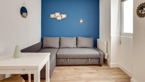 A modern living room with a grey sofa, a white table, and a blue accent wall.