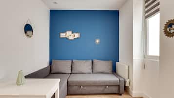 En moderne stue med en grå sofa, et hvidt bord og en blå væg.