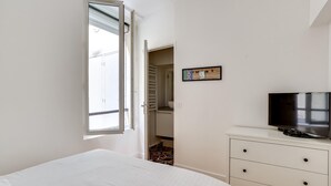 A bedroom with a bed, a television, a wardrobe, and a window.