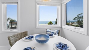 A dining area with a view of the sea, white walls, and a chandelier. - Penthouse! Steps from Victoria Beach, 180 degree ocean views! (Laguna Beach)