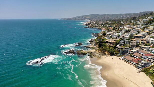 A coastal town with a sandy beach and ocean waves crashing onto the shore.