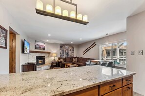 A modern kitchen with a granite countertop, a fireplace, and a dining area with a table and chairs.
