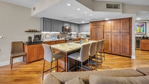 A modern kitchen with a marble island, wooden cabinets, and a built-in oven.