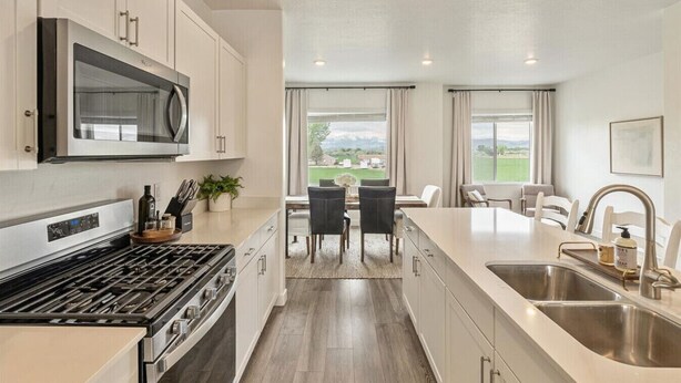 A modern kitchen with stainless steel appliances, a dining area with a view, and a large island with a sink.