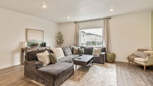 A modern living room with a sectional sofa, a small coffee table, and a view of the street outside.