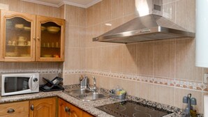Una cocina con armarios de madera, una campana extractora de acero inoxidable, un microondas, un fregadero y encimeras de granito.