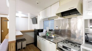 Una cocina compacta con armarios blancos, una estufa de acero inoxidable y un microondas integrado.