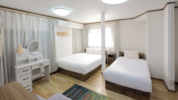 Habitación de hotel con dos camas, un escritorio con espejo y una mesita de noche.