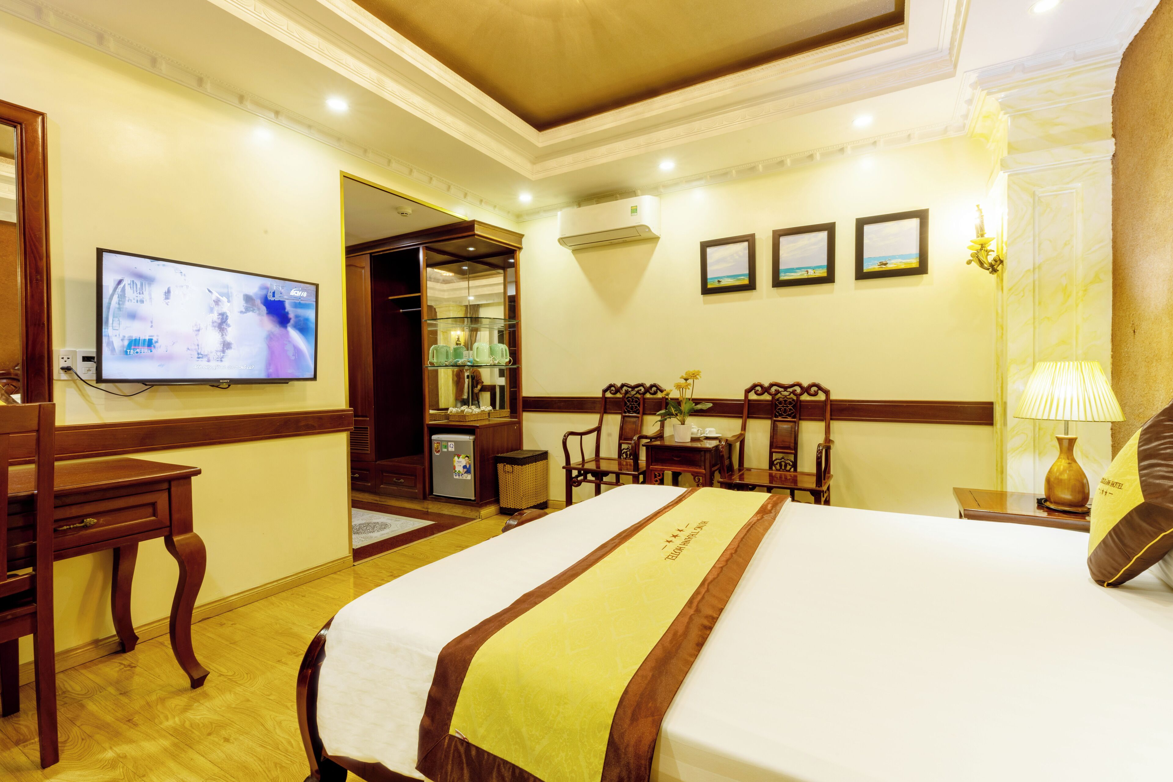 A hotel room with a large bed, a television, a desk, and a dining area.