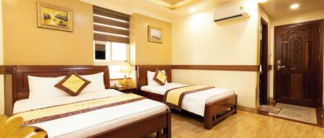 A hotel room with two beds, a wooden floor, a wall-mounted air conditioner, and a door with a decorative handle.