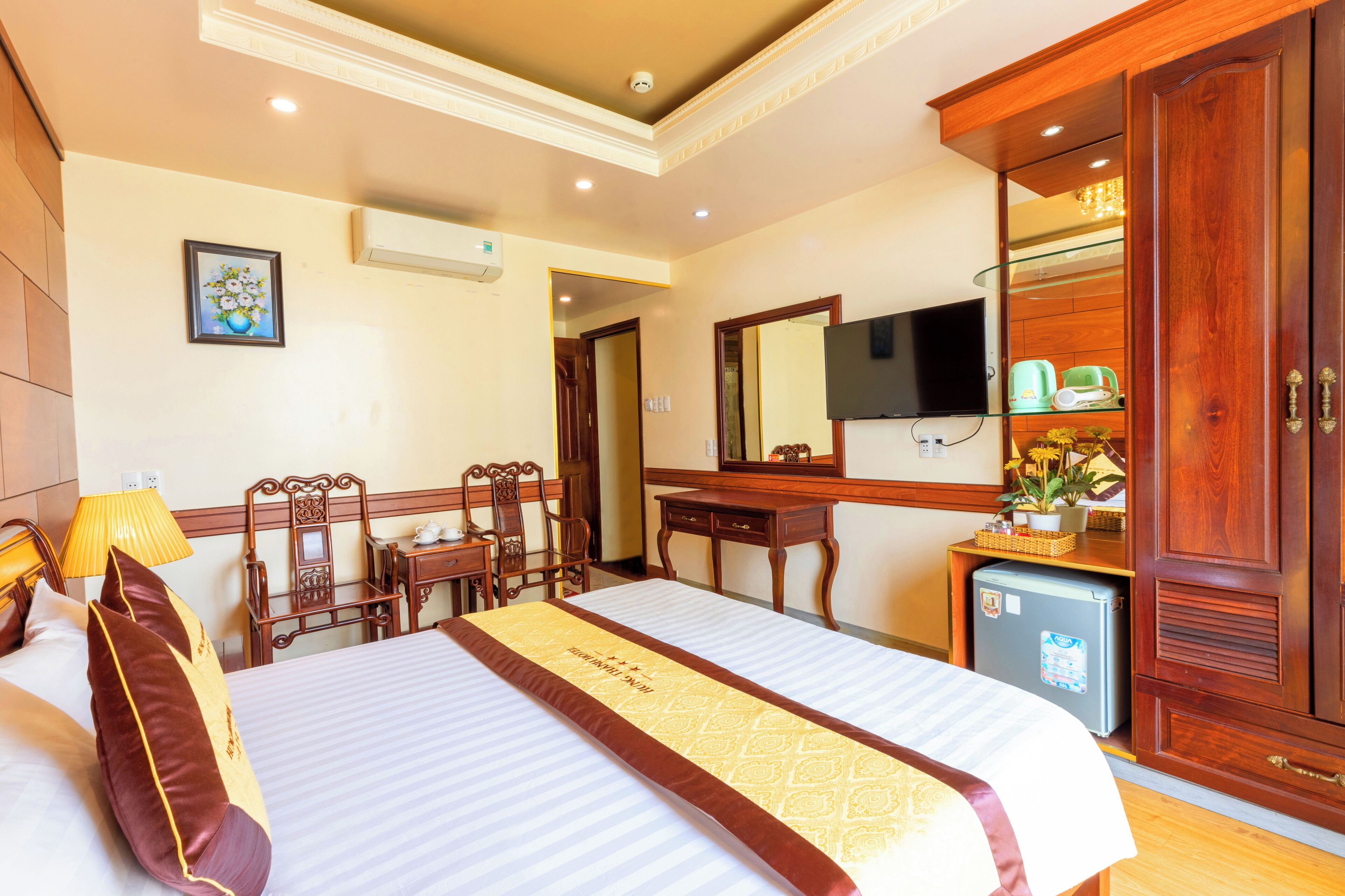 Habitación de hotel con cama, escritorio, silla, televisor y armario.