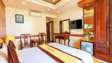 Habitación de hotel con cama, escritorio, silla, televisor y armario.