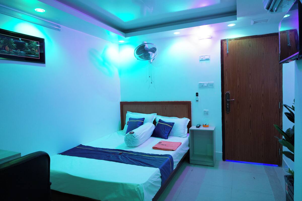 A bedroom with a bed, bedside table, nightstand, and a wooden door.