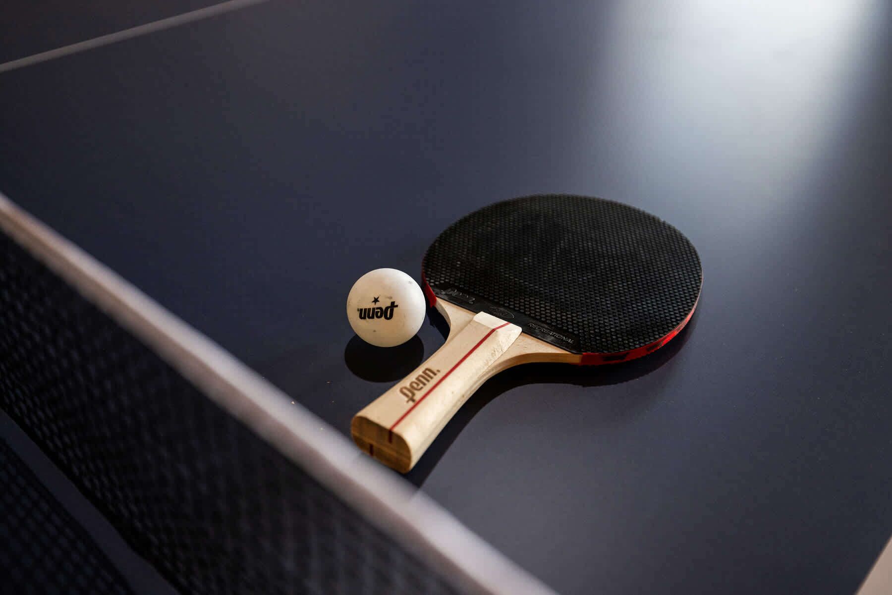 A table tennis table with a paddle and a ball.