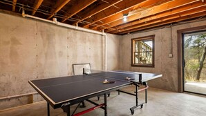 Una mesa de ping pong en una habitación con vigas de madera a la vista y suelo de hormigón.