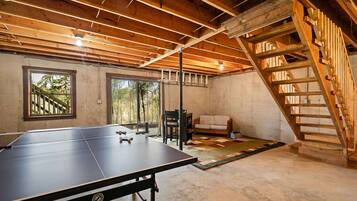 Una stanza con un tavolo da ping pong, una poltrona e una scala.