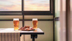 Zwei Biergläser auf einem Holztisch, dazu Brezeln und Käse.
