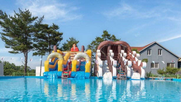Ein Schwimmbecken mit aufblasbaren Rutschen und einer Wasserrutsche.