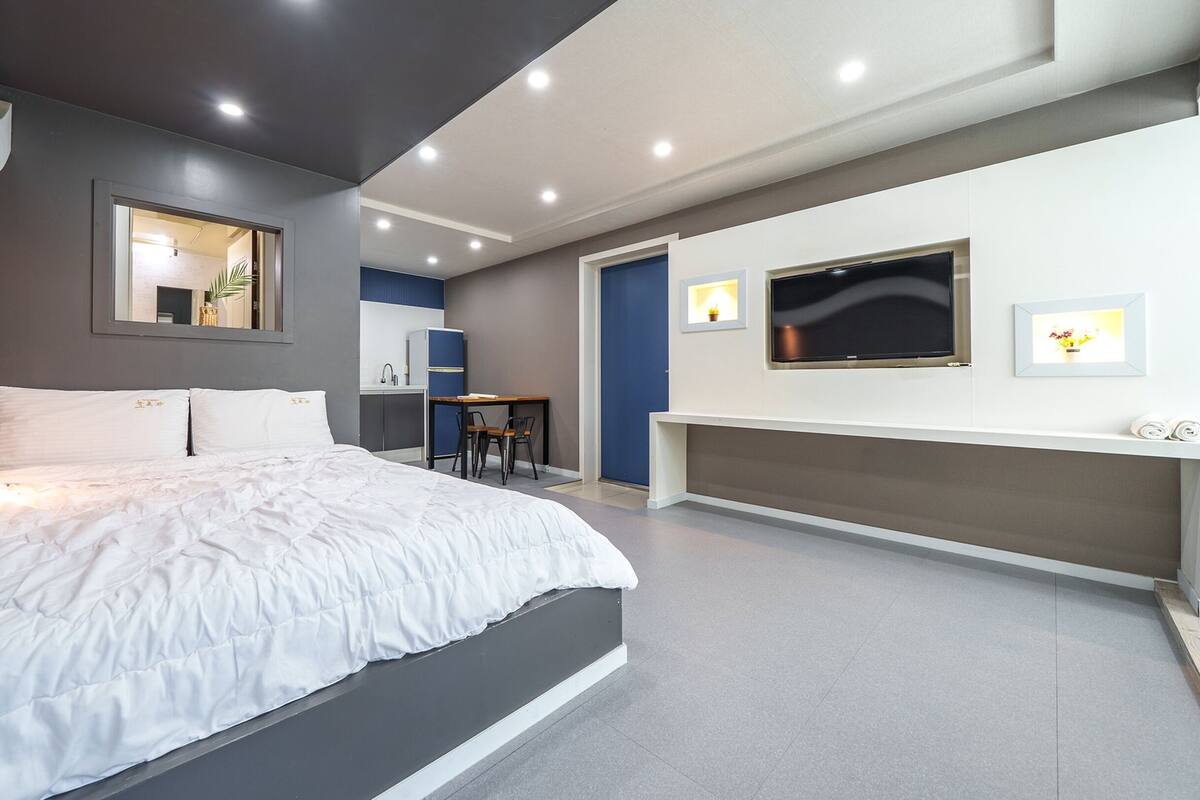 A modern bedroom with a large bed, a TV, and a desk area.