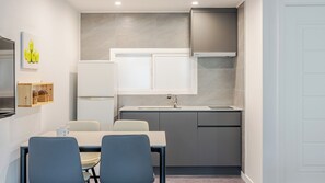A compact kitchen with a dining area, featuring a refrigerator, cabinets, and a sink. - Gyeongju Nollowa Spa Pension (Gyeongju)