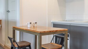 A small kitchenette with a wooden table and two chairs, a white door, and a white tiled wall. - Gyeongju Nollowa Spa Pension (Gyeongju)