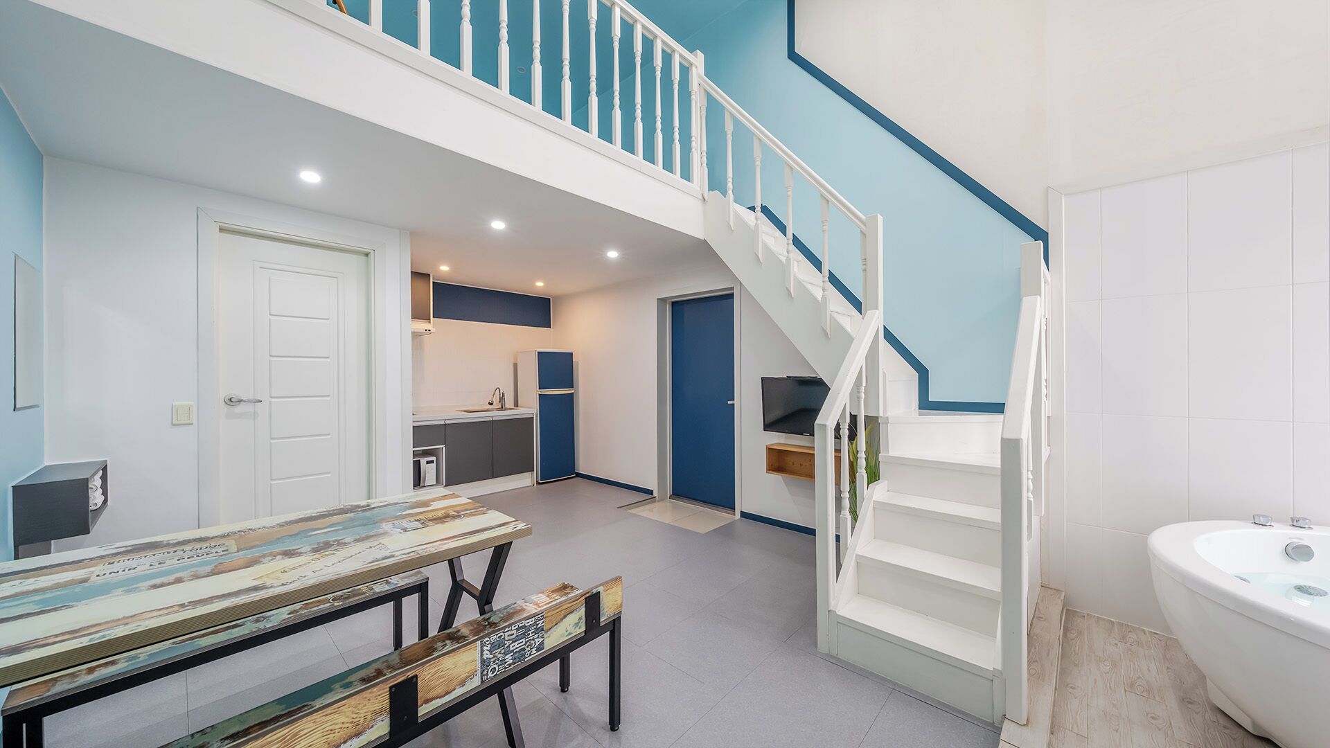 A modern interior with a staircase, a kitchen, and a dining area.