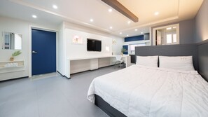 Ein modernes Hotelzimmer mit einem großen Bett, einem Fernseher, einem Schreibtisch und einem Badezimmer.