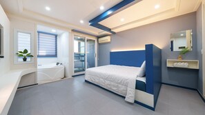 Ein modernes Schlafzimmer mit Bett, integrierter Badewanne und einer Schiebeglastür zum Badezimmer.