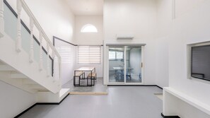 Ein modernes Interieur mit einer Treppe, einem Tisch mit Bänken, einer Schiebeglastür und einem Wandfernseher.