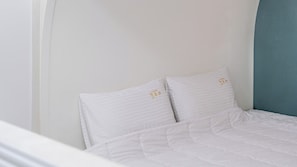 A bed with white bedding and pillows, a blue headboard, and a plain wall. - Gyeongju Nollowa Spa Pension (Gyeongju)
