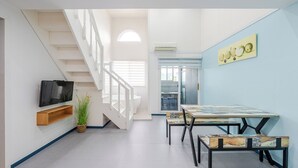 Ein modernes Interieur mit Treppe, Flachbildfernseher, Esstisch mit Stühlen und einer Wand-Klimaanlage.