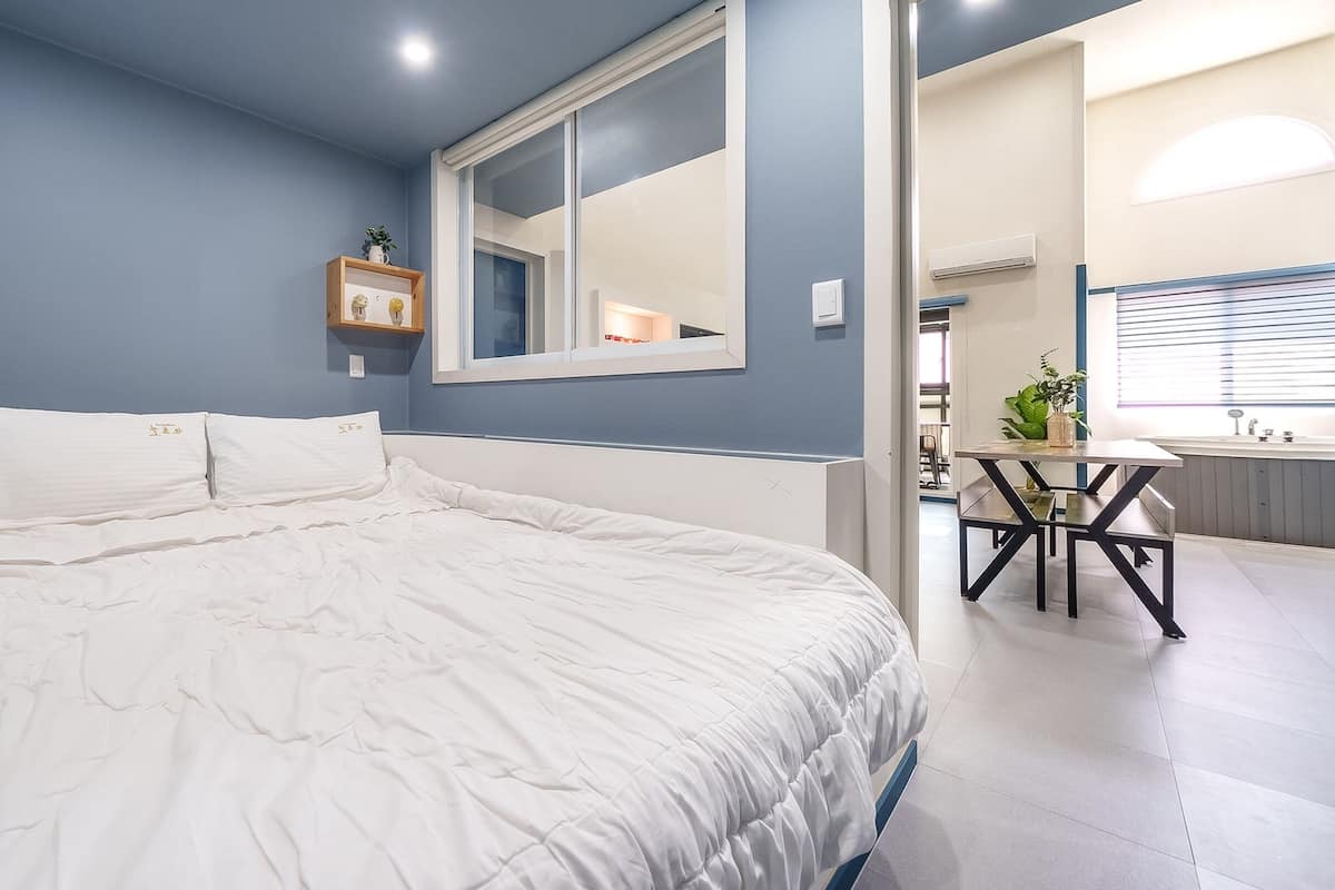 A bedroom with a large bed, a mirror, and a small table with chairs.