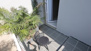 A small balcony with a chair and potted plants, a window, and a tiled floor. - Vaishnav Hotel (Latur)