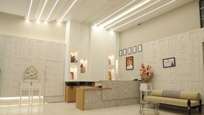 A reception area with a marble reception desk, a sofa, and a small table with a vase of flowers. - Vaishnav Hotel (Latur)