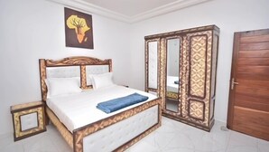A bedroom with a bed, a wardrobe, a mirror, and a door.