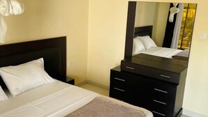 A hotel room with a bed, a nightstand, a dresser, and a large mirror. - Le Fabuleux- Standing ,SV CITY Virage Yoff, Dakar (Dakar)