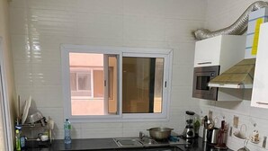 A modern kitchen with dark cabinets, a stainless steel sink, and a window. - Le Fabuleux- Standing ,SV CITY Virage Yoff, Dakar (Dakar)