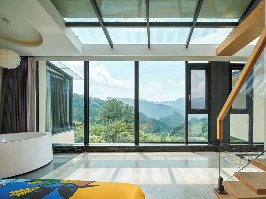 A modern room with a large skylight, a curved white sofa, and a view of a mountainous landscape.