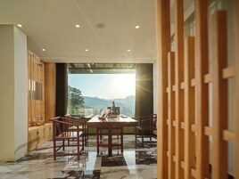 Un comedor con una mesa grande y sillas, un separador de madera, y vistas a montañas a través de un ventanal.