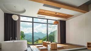 A modern bathroom with a large bathtub, wooden flooring, and a view of mountains through large windows. - Serenity Valley - Zhangjiajie (Zhangjiajie)