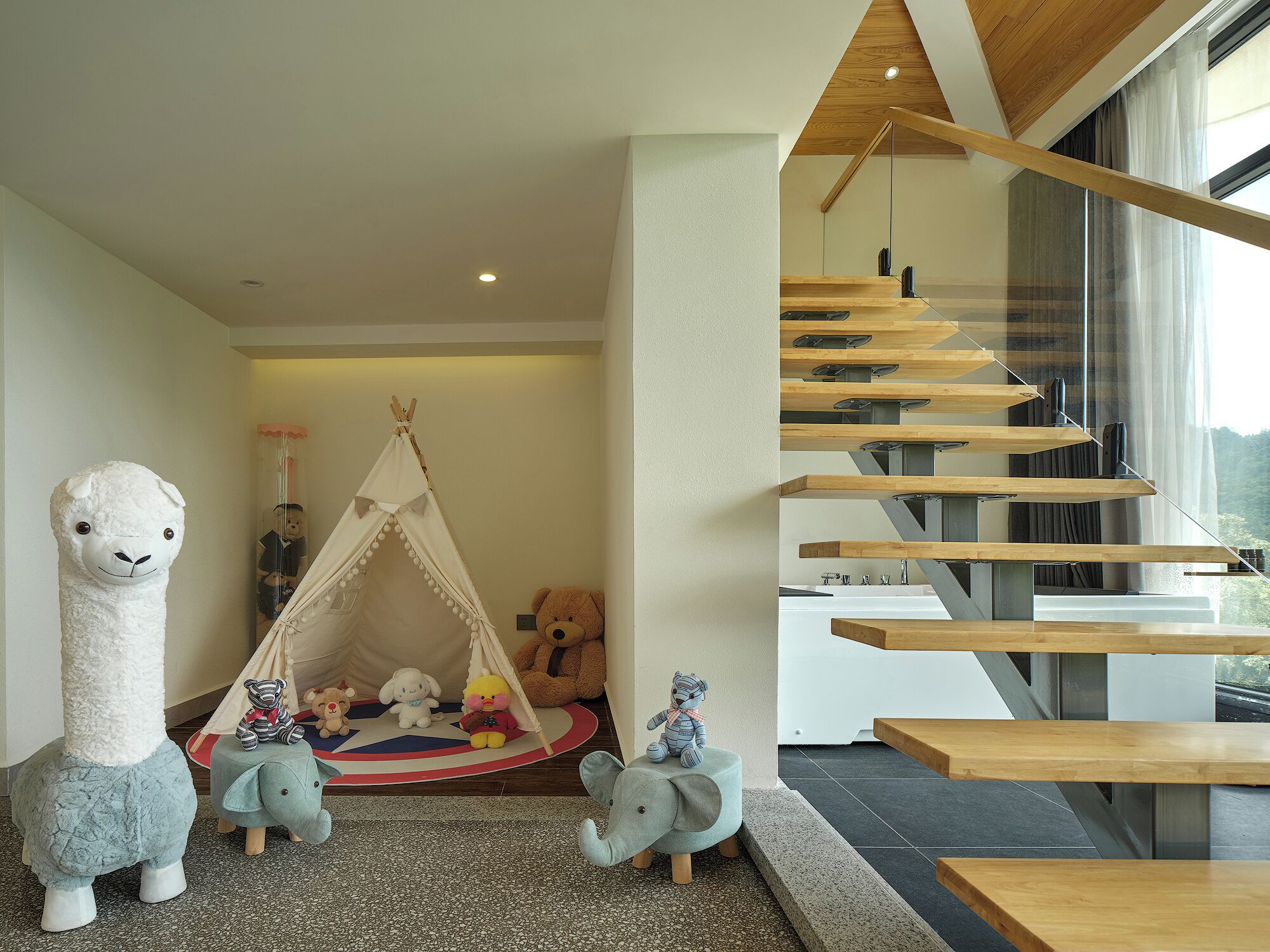 Um interior moderno com escada de madeira, área de recreação com bichos de pelúcia e uma grande janela com vista.