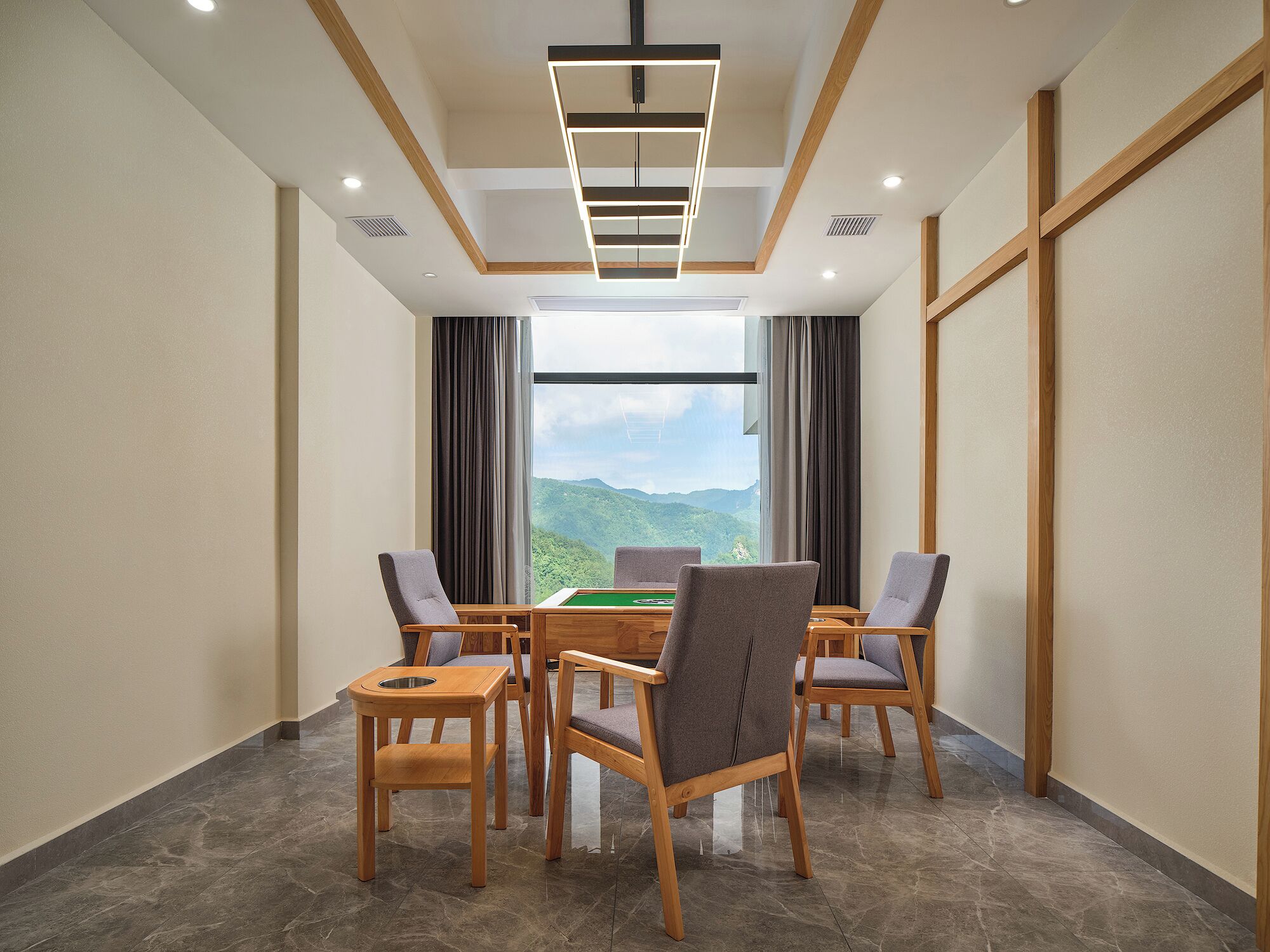A conference room with a pool table, four chairs, and a view of mountains through large windows.