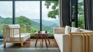A modern living room with a large window, a sofa, a chair, and a small round table. - Serenity Valley - Zhangjiajie (Zhangjiajie)