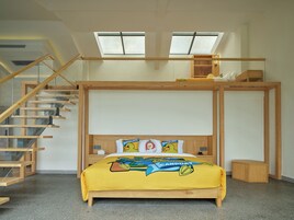Una habitación con literas, tragaluces, una escalera de madera y una pequeña mesita de noche.