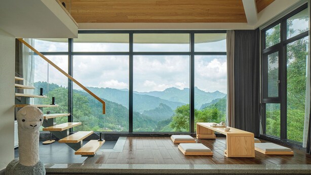 A modern interior with a large window offering a mountain view, a wooden staircase, and a plush llama sculpture. - Serenity Valley - Zhangjiajie (Zhangjiajie)